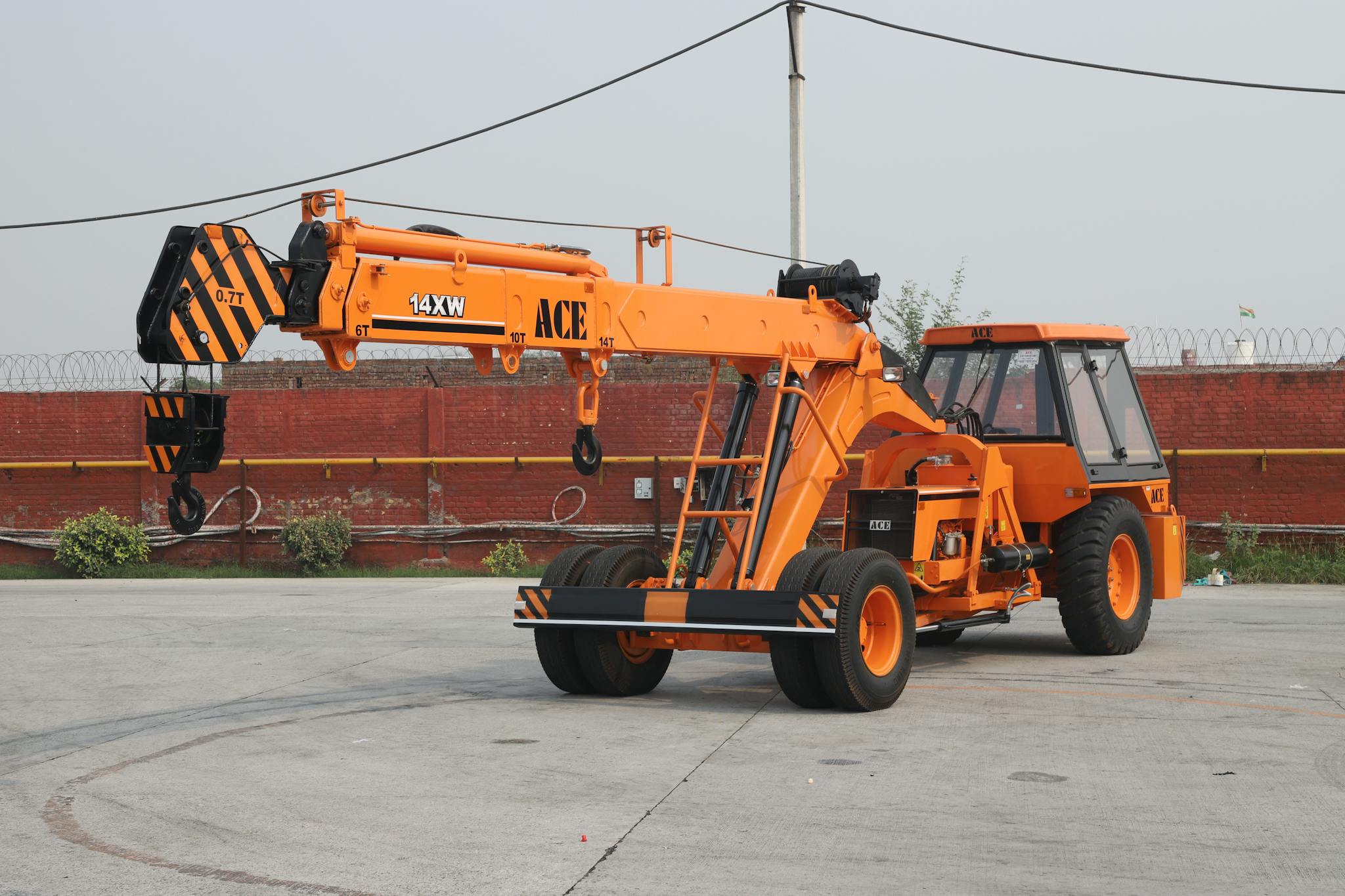 Orange ACE 14XW mobile crane in an industrial outdoor setting in India.